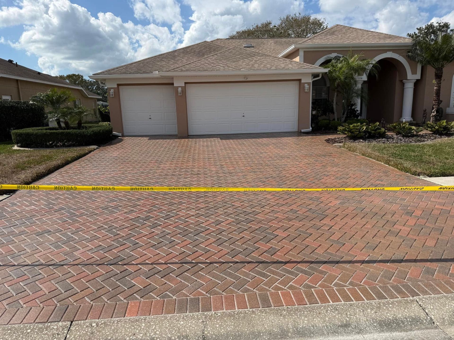 A brick driveway in front of a house with a yellow tape around it