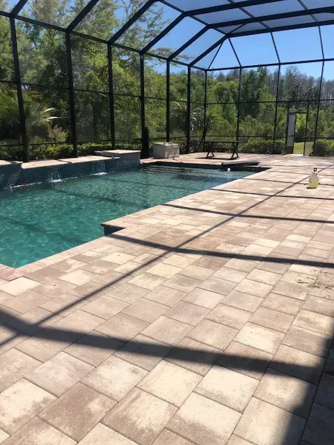 A large swimming pool is surrounded by a screened in area.