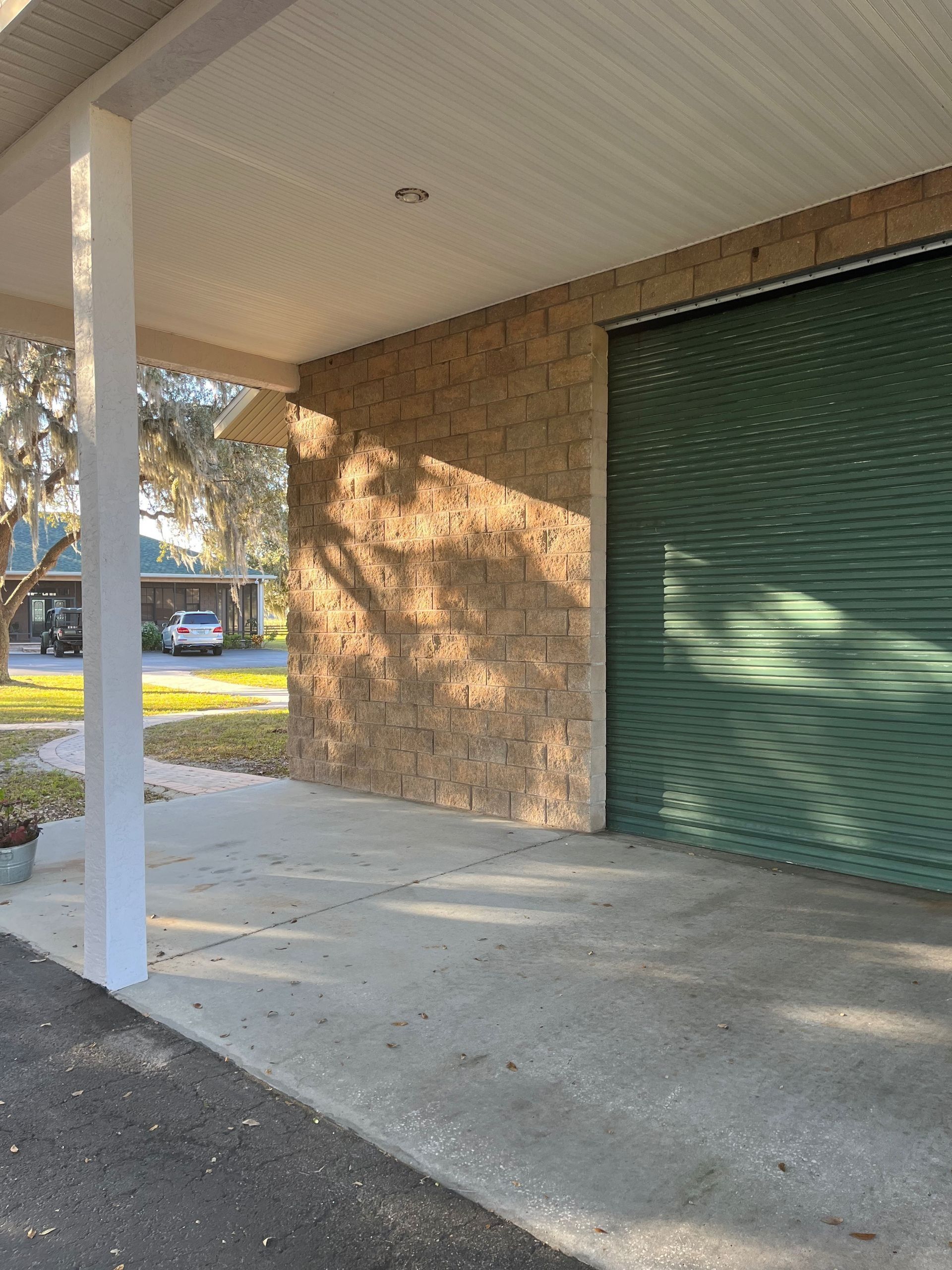A green garage door is next to a brick building.
