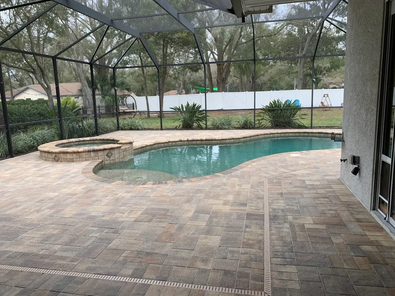 A large swimming pool is surrounded by a screened in area.