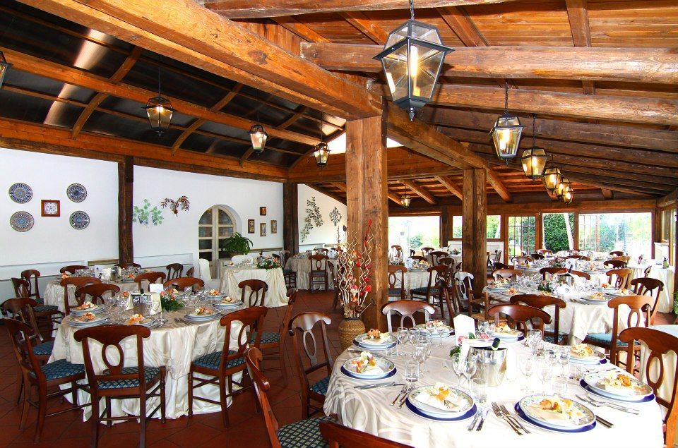 Interno del ristorante con travi in ​​legno, tavoli apparecchiati per i commensali.