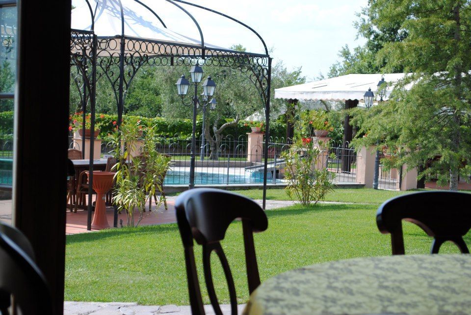 Vista di un cortile con piscina, gazebo e prato verde dall'interno di un edificio.