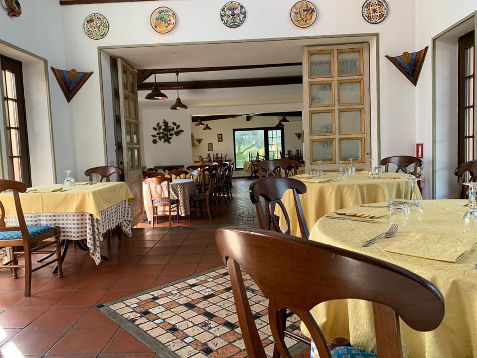 Sala da pranzo del ristorante con tovaglie gialle, sedie in legno, porta aperta su un'altra sala da pranzo.