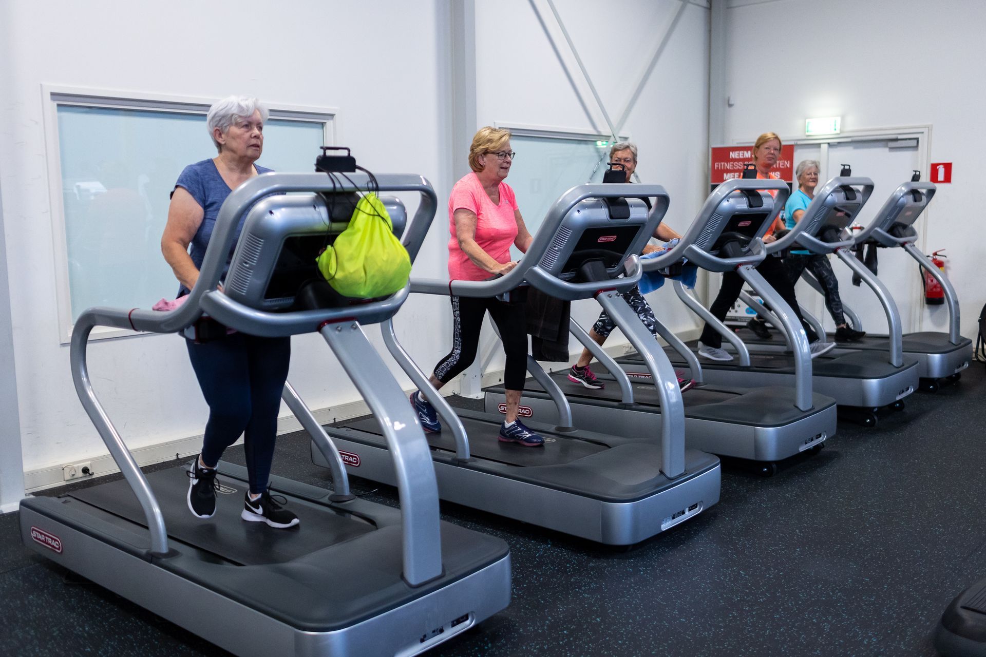 Vrouwen trainen op een loopband in een sportschool.