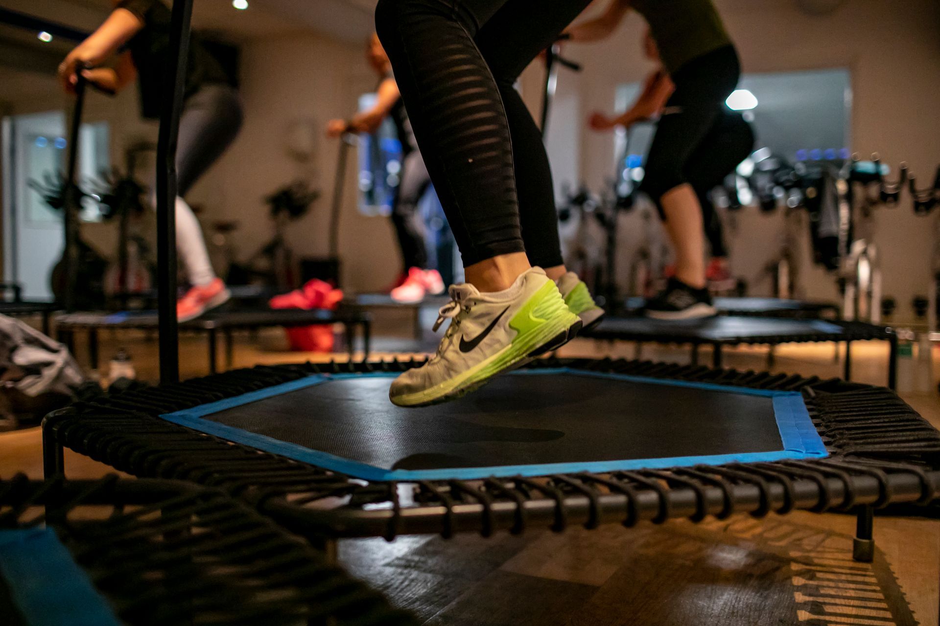 Mensen springen op minitrampolines in een sportschool en doen oefeningen.