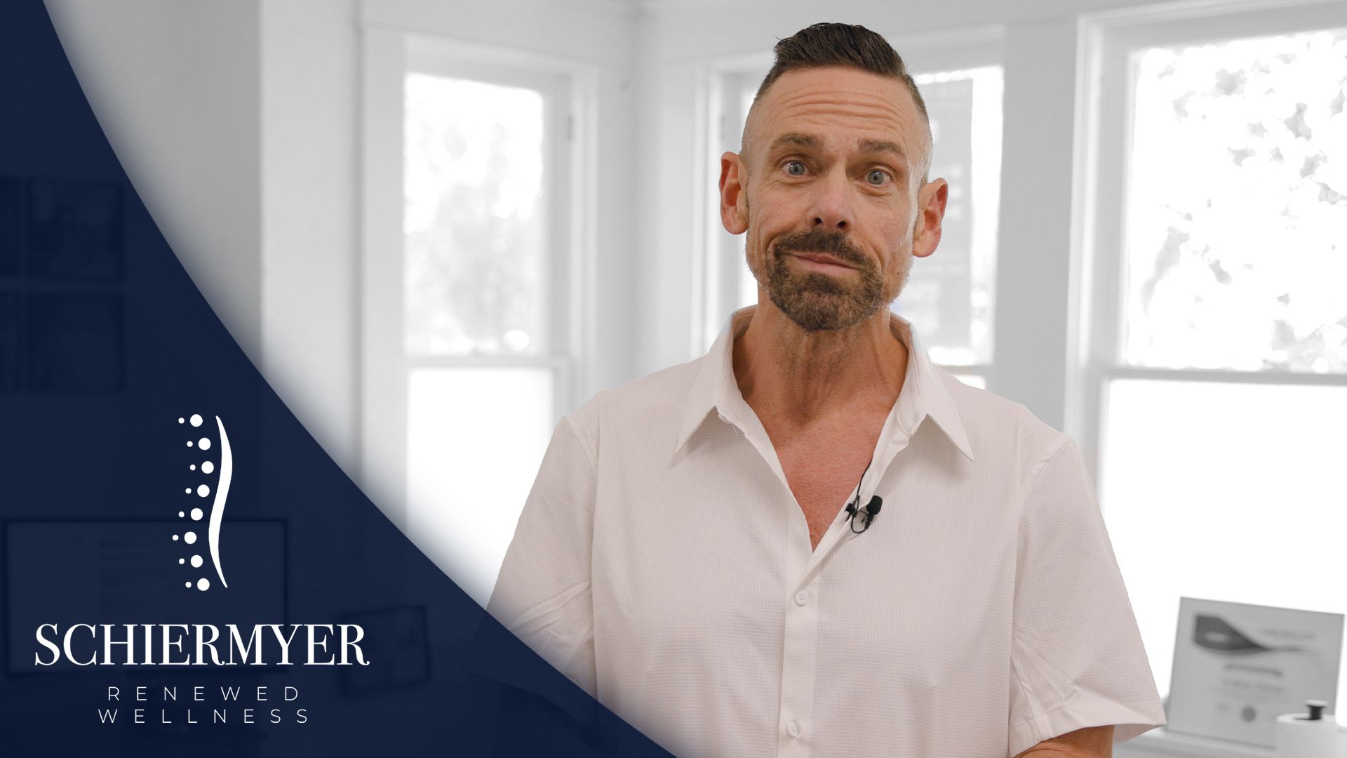 Man in white shirt in a bright room, logo on the left.