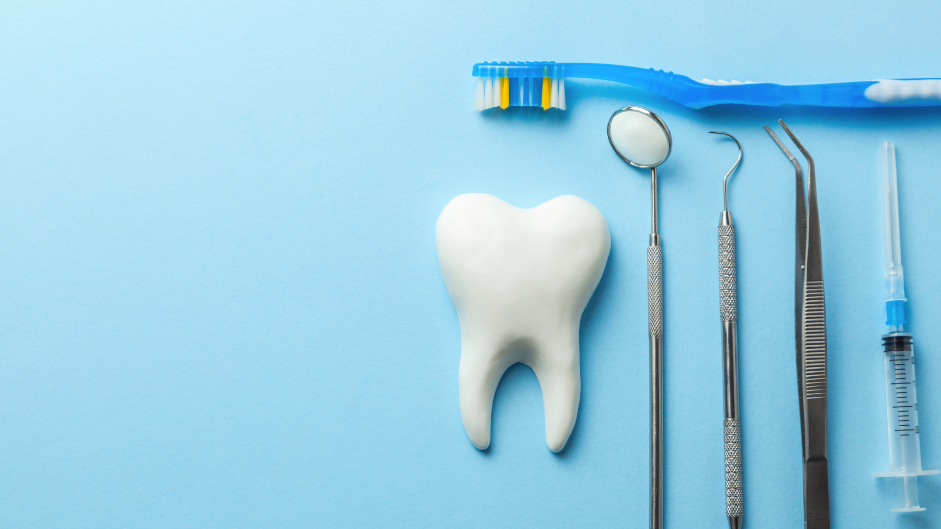 Hand reaching toward dental chair with attached magnification glasses in a dentist's office.