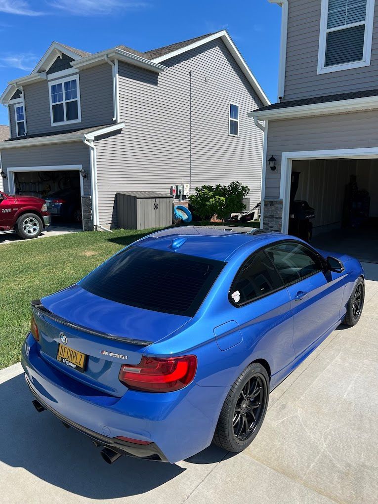 A blue bmw is parked in front of a house.