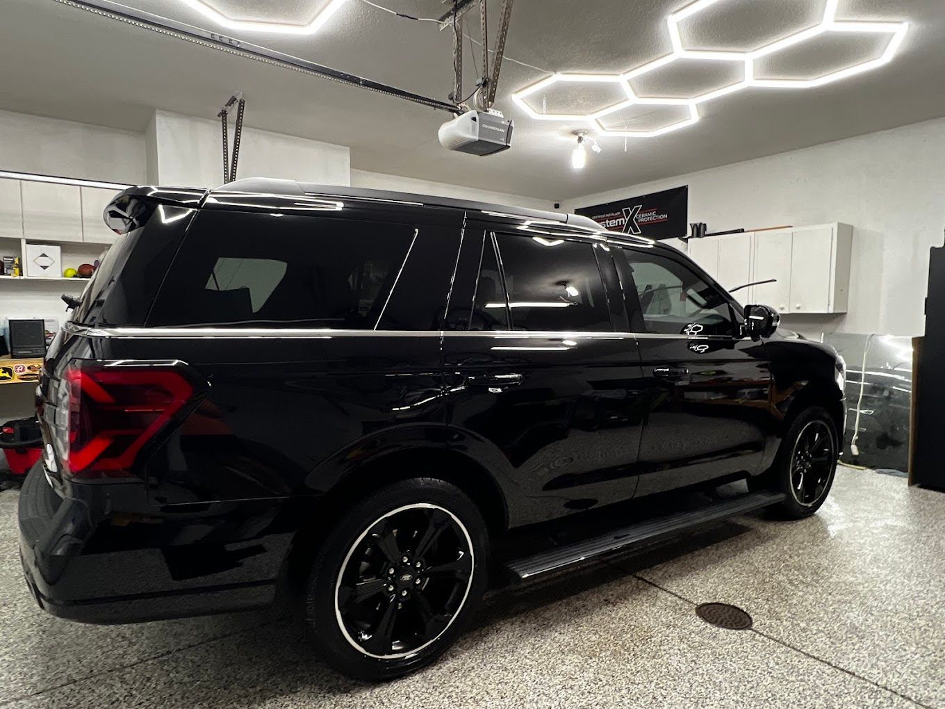 A black suv is parked in a garage under a garage door.