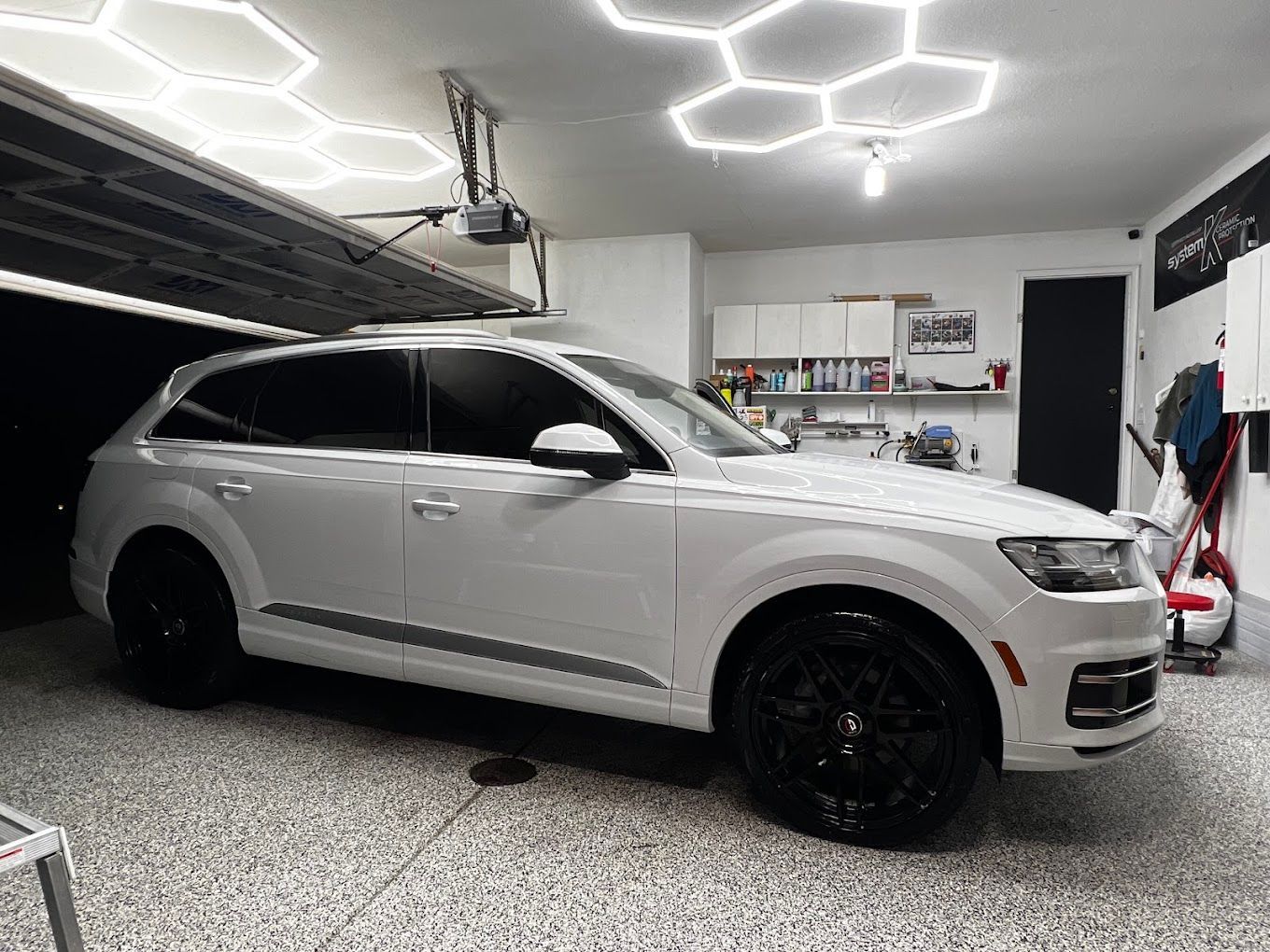A white car is parked in a garage under a garage door.