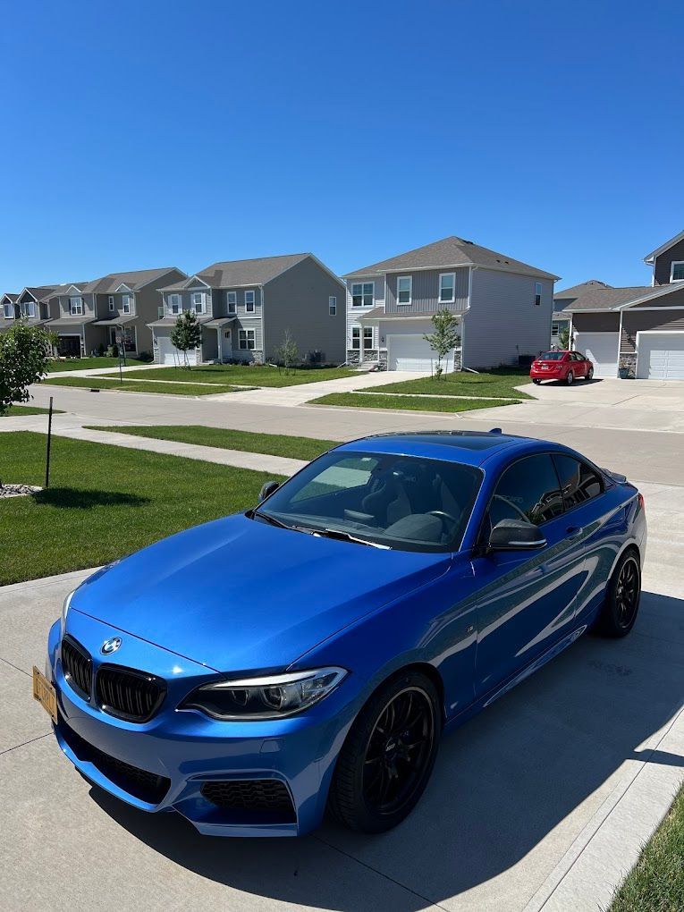 A blue bmw is parked in the driveway of a residential neighborhood.