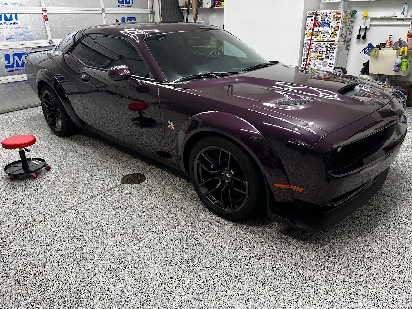 A purple dodge challenger is parked in a garage.