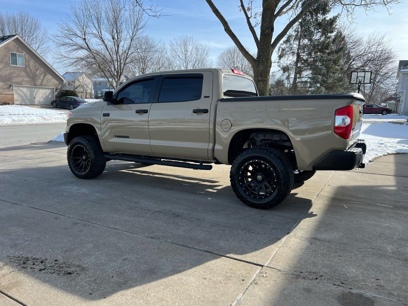 A tan toyota tundra is parked in a driveway.
