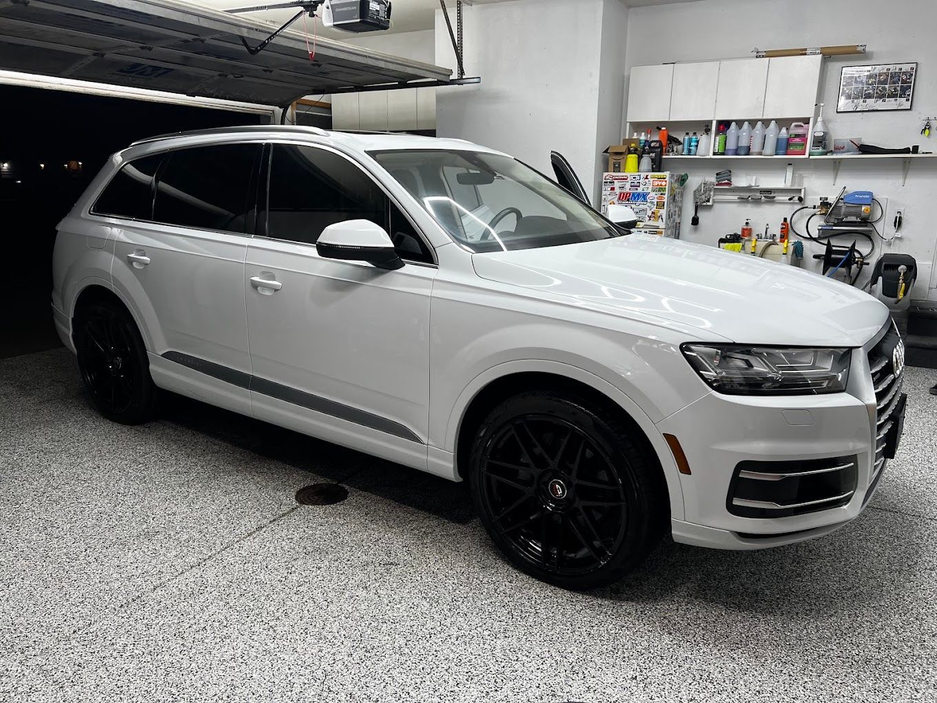 A white audi q7 is parked in a garage.