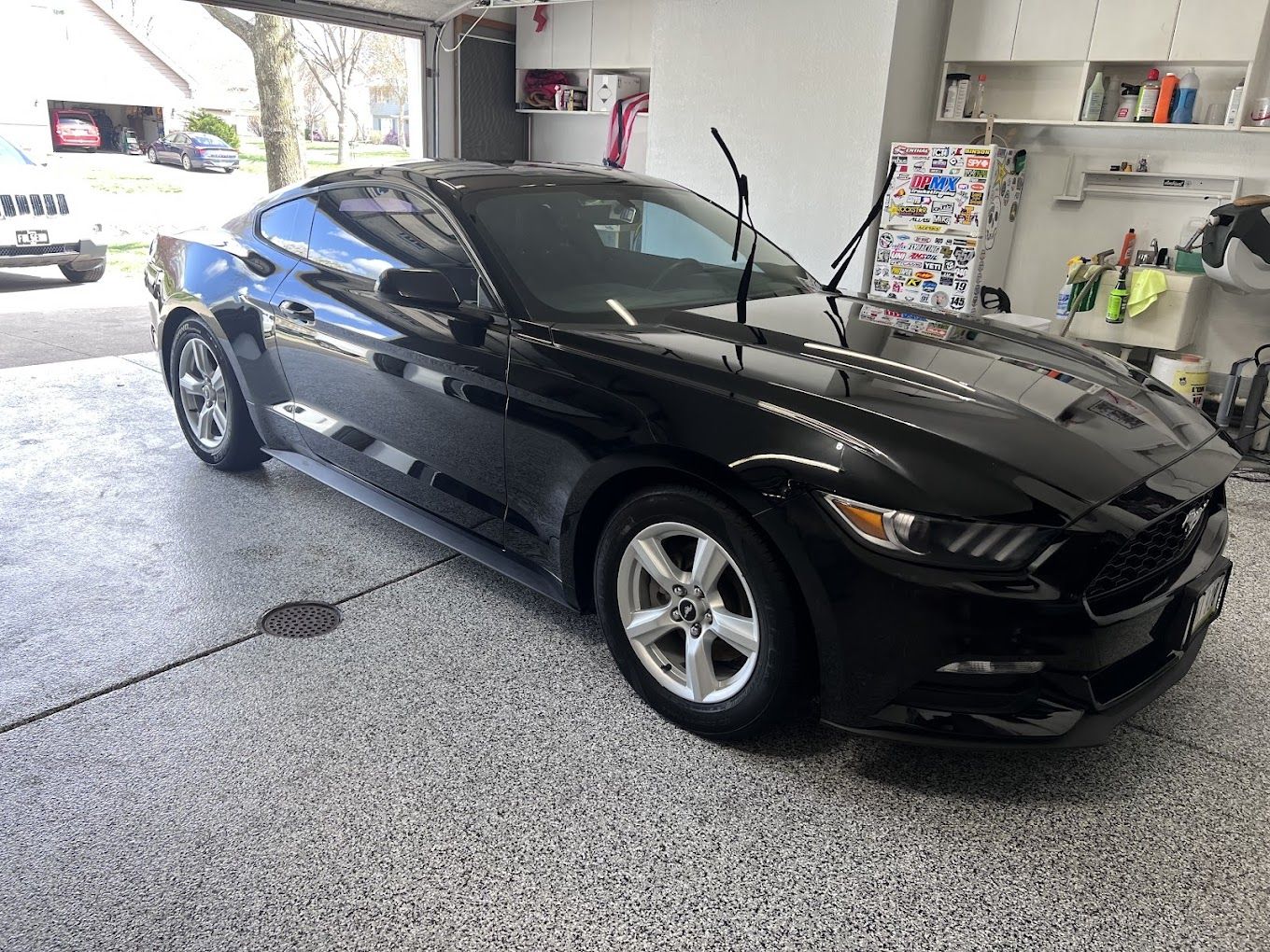 A black mustang is parked in a garage.