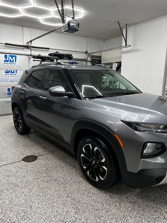 A gray suv is parked in a garage with a roof rack.