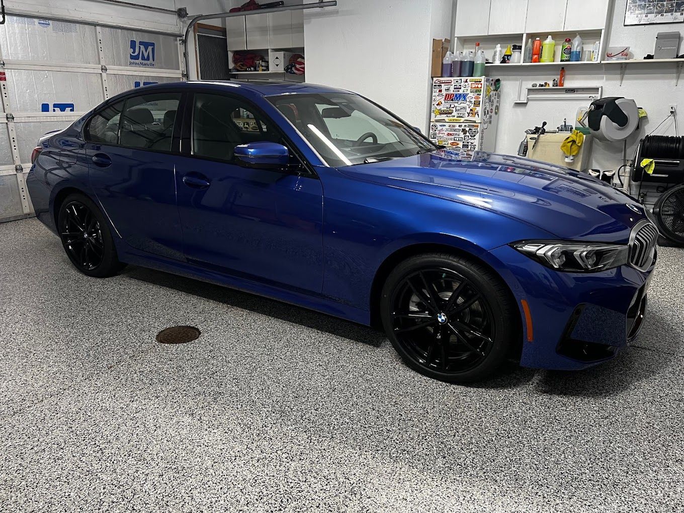 A blue bmw 3 series is parked in a garage.