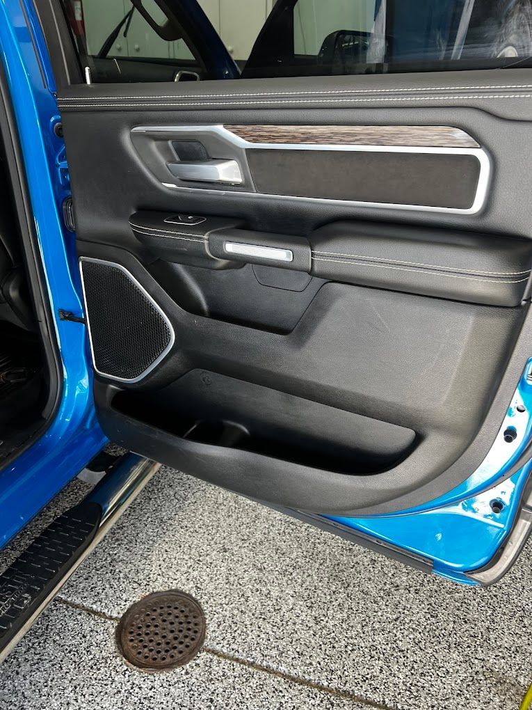 The door of a blue ram truck is open and sitting in a garage.