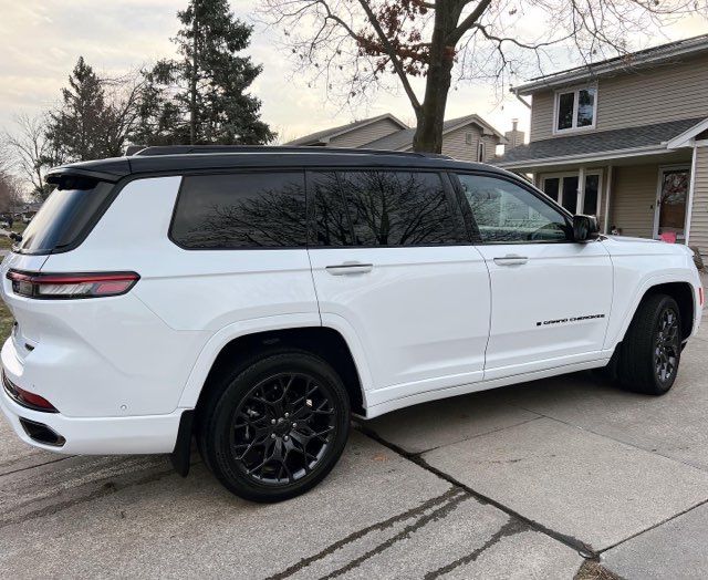A white jeep grand cherokee is parked in a driveway in front of a house.