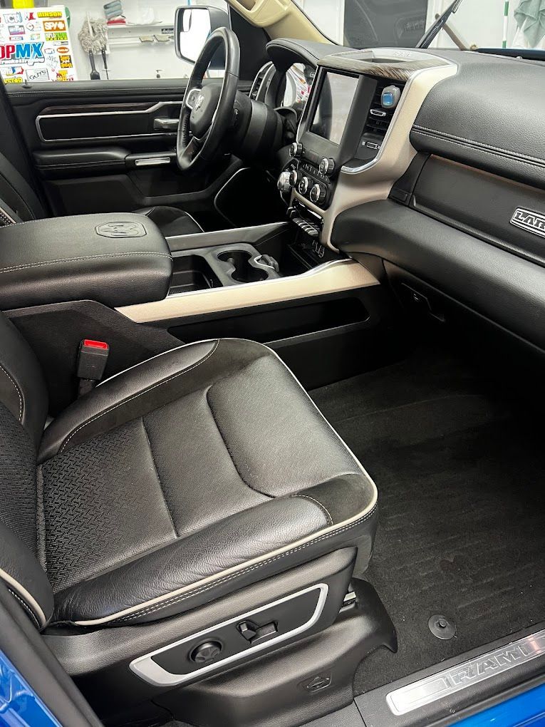 The interior of a blue ram truck with black leather seats.