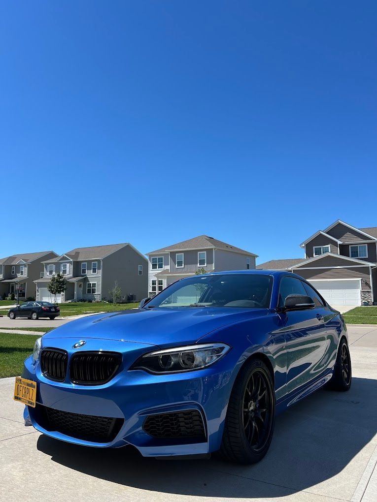 A blue bmw is parked in a driveway in front of a house.