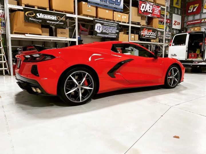 A red sports car is parked in a garage.