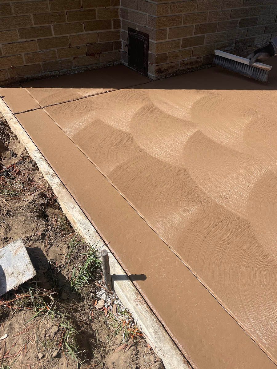A concrete walkway is being built next to a brick wall.