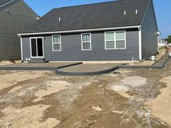 The back of a house with a concrete patio in front of it.