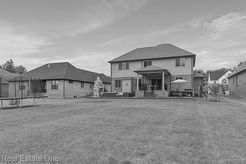 A black and white photo of a house with a large lawn in front of it.
