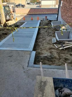 A concrete walkway is being built next to a brick building.