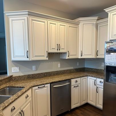 A kitchen with white cabinets , granite counter tops , stainless steel appliances and a sink.