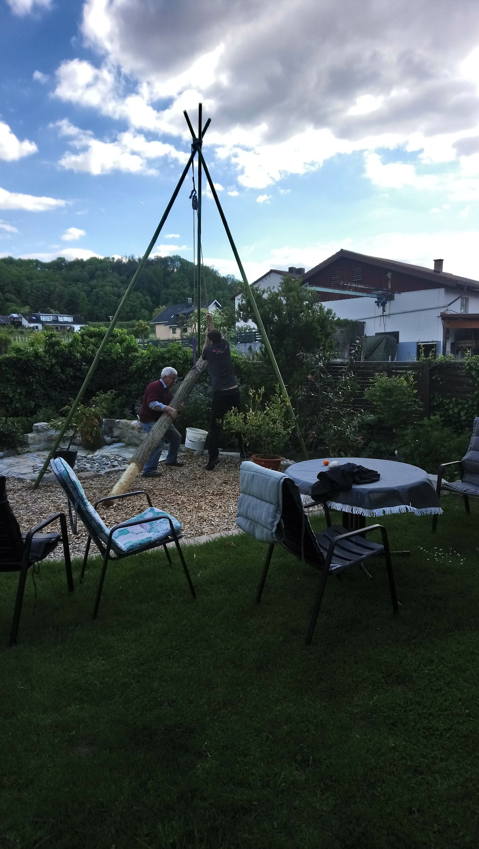 Ein Mann fällt in einem Hinterhof mit einem Tisch und Stühlen einen Baum.