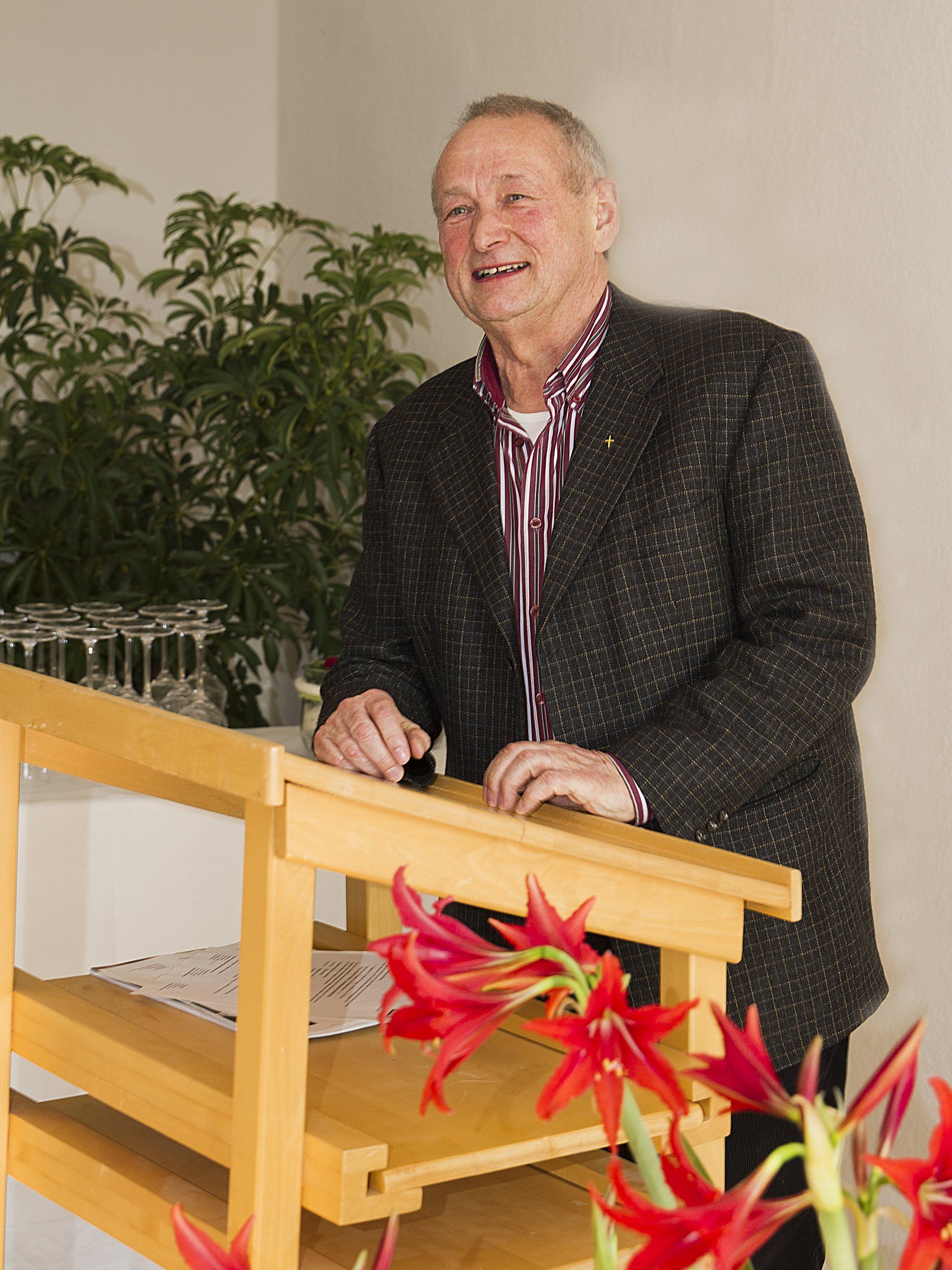 Ein Mann steht an einem Podium mit roten Blumen vor ihm