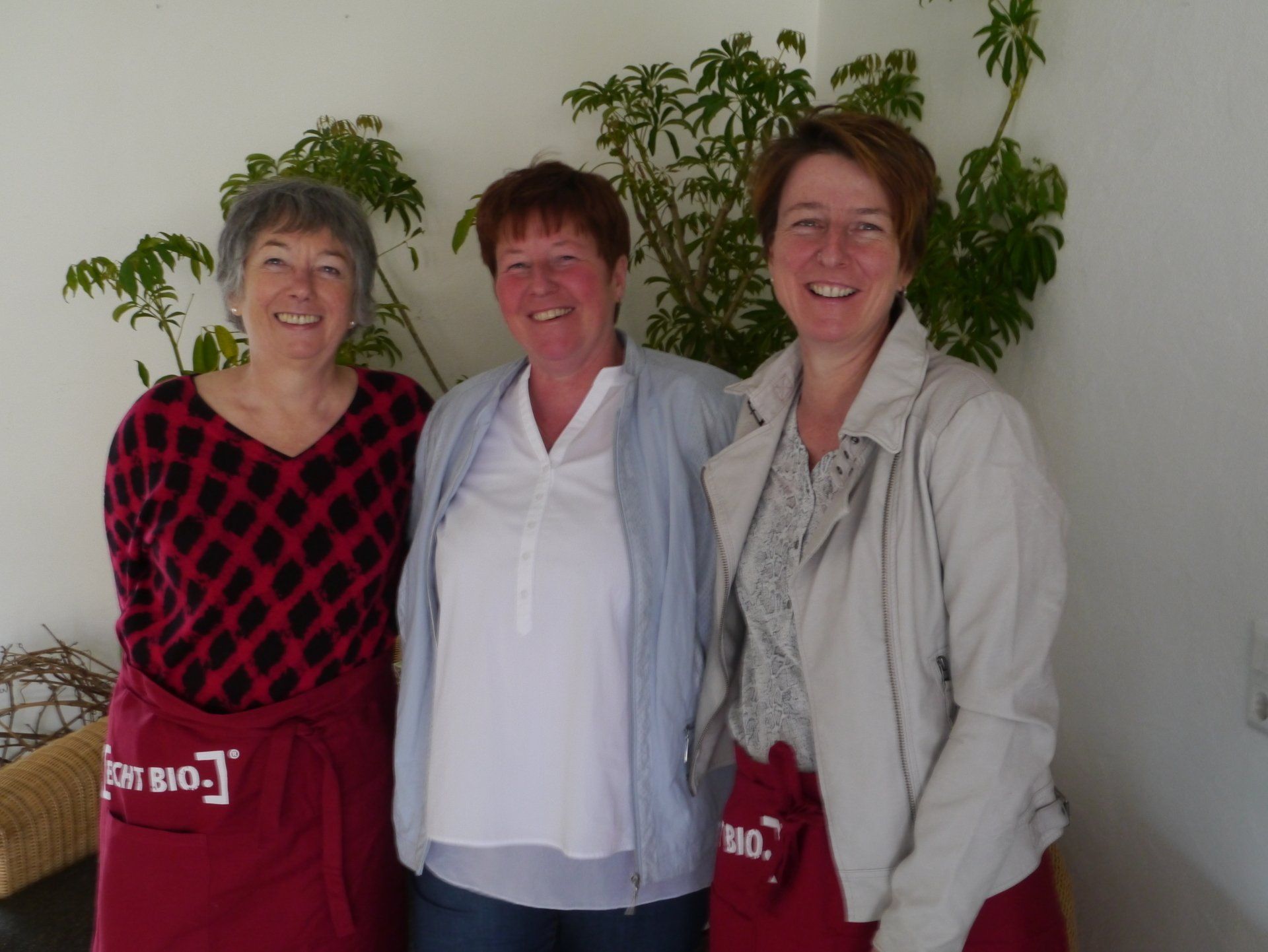 Drei Frauen posieren für ein Foto, eine trägt eine rote Schürze mit der Aufschrift „Big Bag“