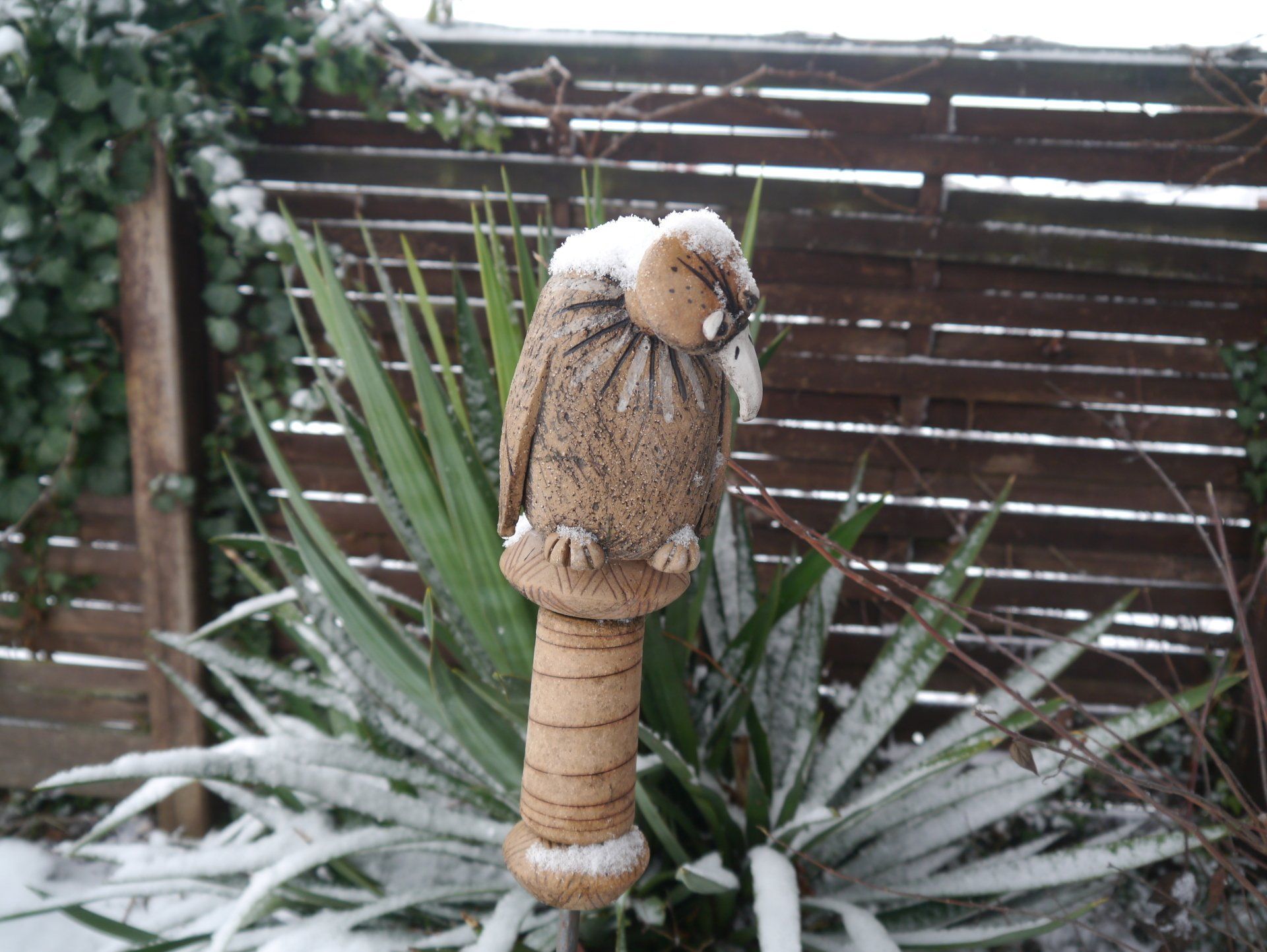 Eine Statue einer Eule, die auf einer schneebedeckten Pflanze sitzt