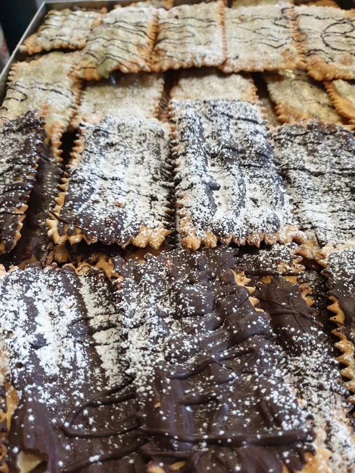 Primo piano di pasticcini rettangolari, alcuni con cioccolato e zucchero a velo, altri con una copertura più leggera.