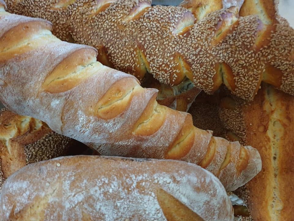 Vari tipi di pane, alcuni spolverati con farina e semi di sesamo.