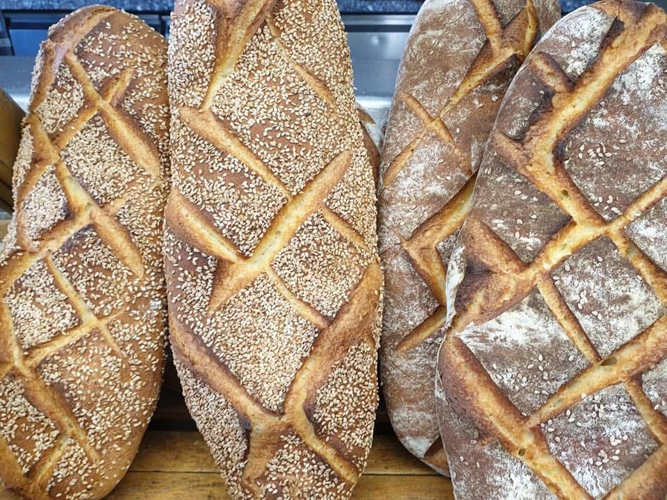 Pagnotte di pane croccante con incisioni a forma di diamante, alcune con semi di sesamo.