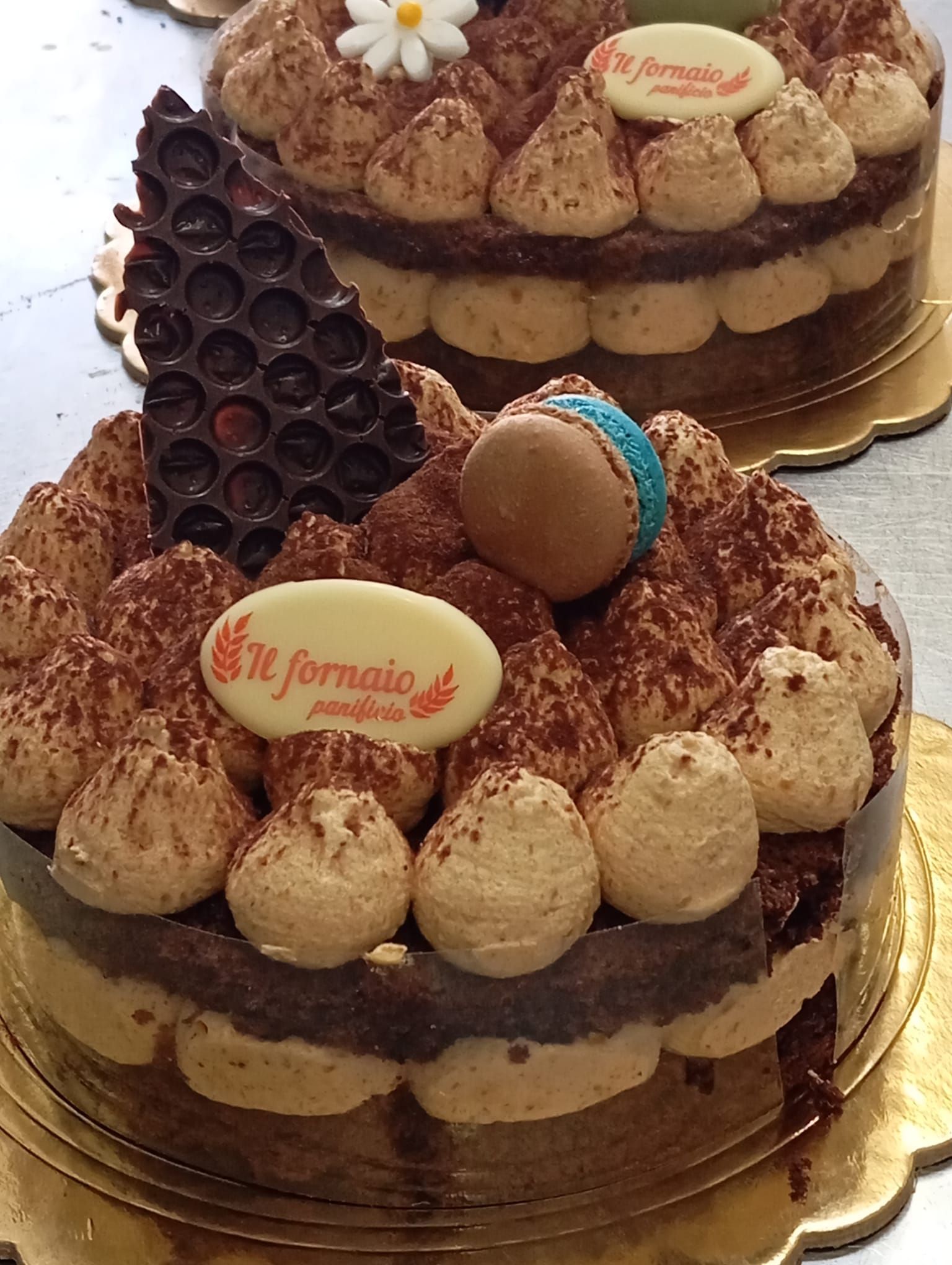 Torta al cioccolato con crema di copertura, decorazioni in cioccolato e logo commestibile su un vassoio d'oro.