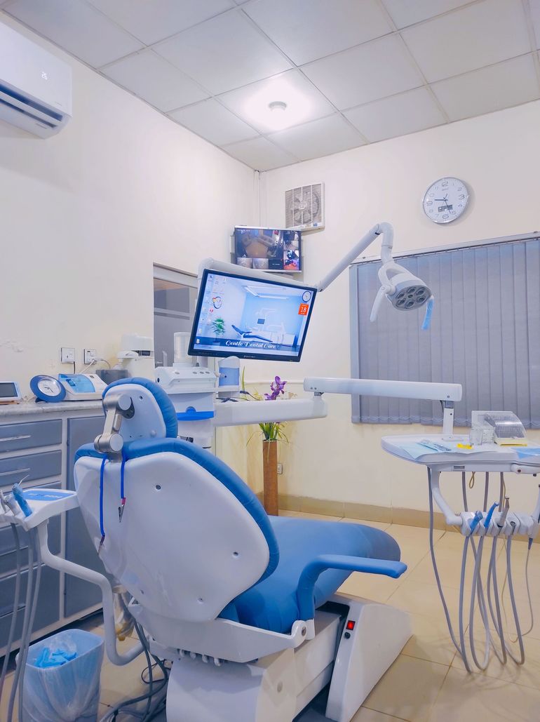 Dental clinic chair with monitor, dental tools, and overhead light in a bright treatment room
