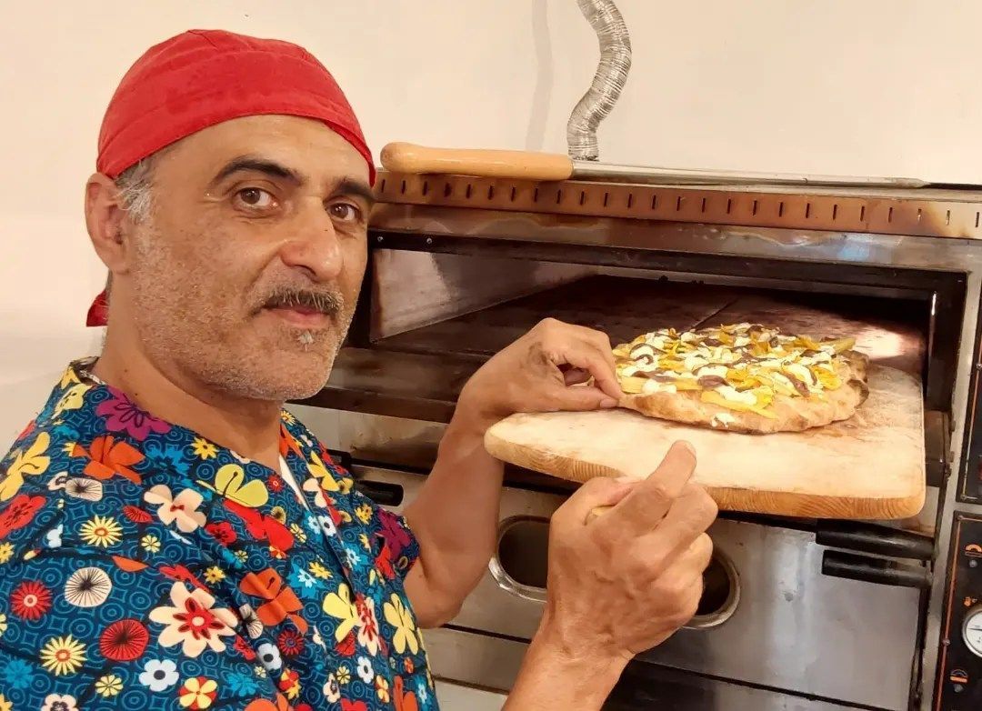 Puccio, tirolare della pizzeria, che inforna una pizza farcita