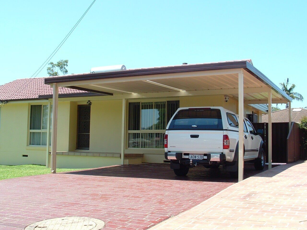 A White Truck is Parked Under a Carport in Front of a House — Hunter & Mid Coast Patios In Lake Macquarie, NSW
