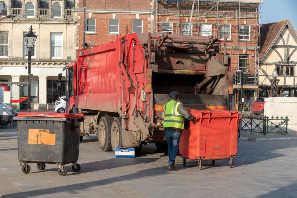 A Man is Loading Garbage Into a Garbage Truck — Gardners Yamba Skip Bin Hire in Gulmarrad, NSW