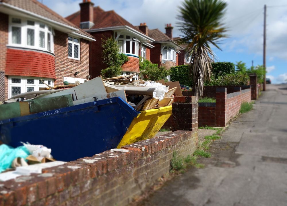 A Row of Houses With a Blue Dumpster in Front of Them — Gardners Yamba Skip Bin Hire in Iluka, NSW
