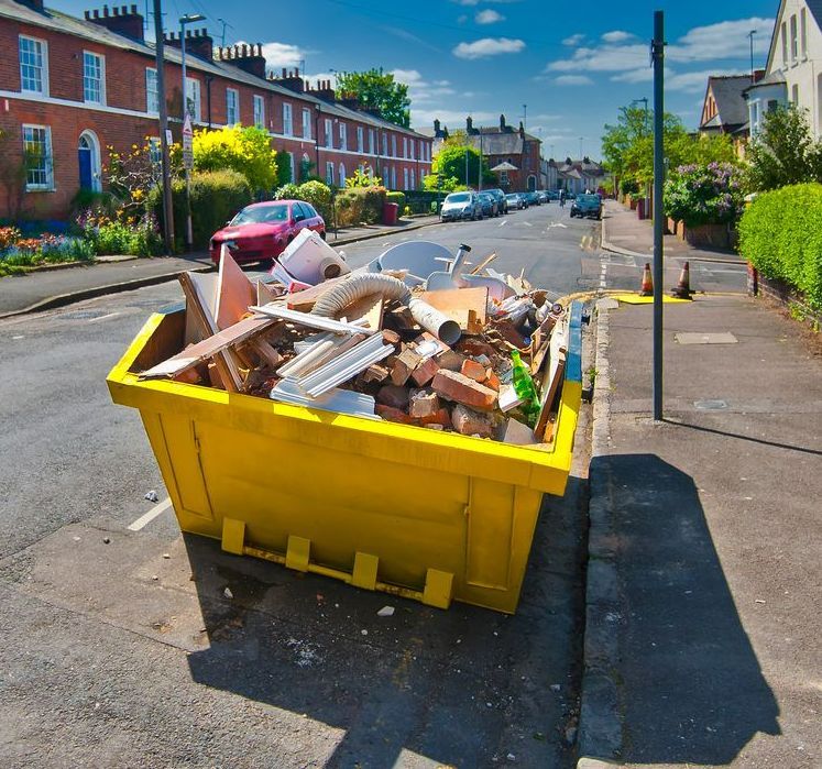 A Yellow Dumpster Filled With Garbage Sits on the Side of a Street — Gardners Yamba Skip Bin Hire in Grafton, NSW