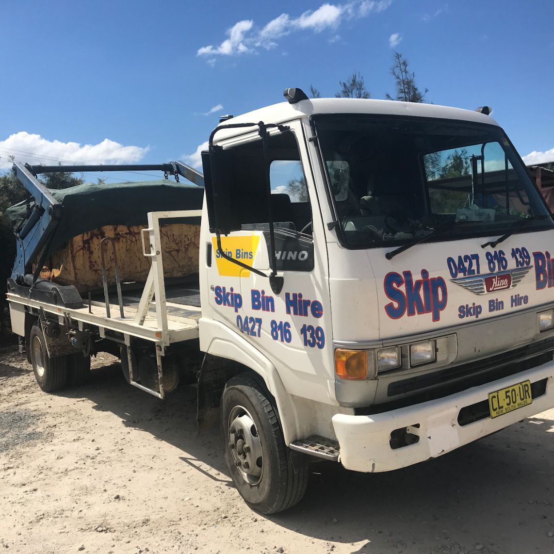 Yellow Rubbish Skip On A Driveway — Gardners Yamba Skip Bin Hire In South Grafton, NSW