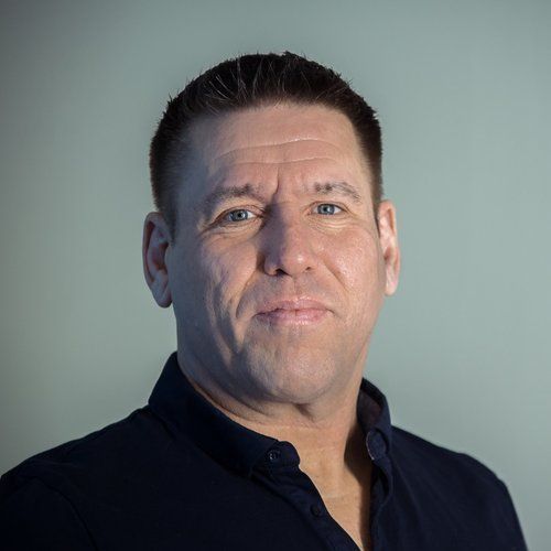 A man in a black shirt is smiling for the camera.