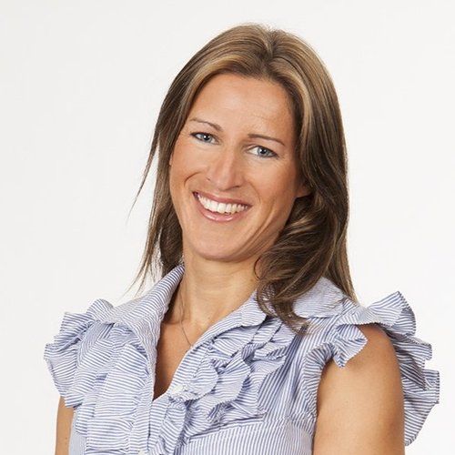 A woman wearing a blue and white striped shirt is smiling for the camera.