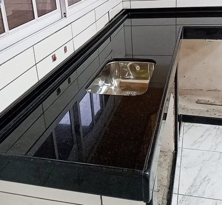 Encimera de granito negro con fregadero de acero inoxidable.