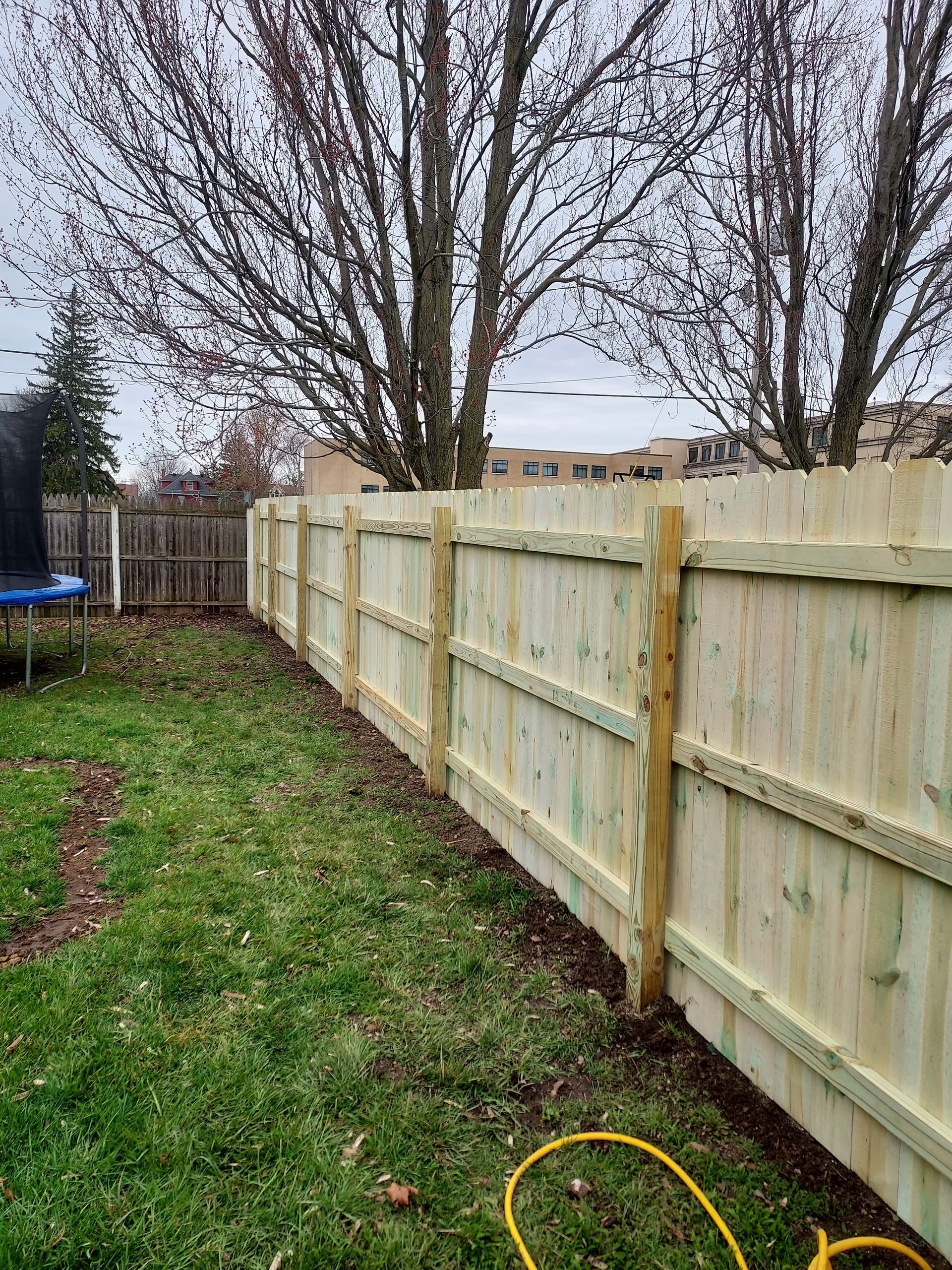 A close up of a wooden fence with trees in the background.